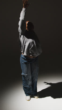 Vertical-Video-Full-Length-Studio-Portrait-Shot-Of-Young-Woman-Dancer-Dancing-In-Slow-Motion-Against-Grey-Background